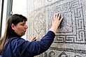 tastende Hände auf eines mosaikbezierten &quot;Teppichs&quot;