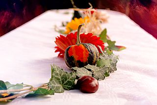 Bildtext: Tischdekoration mit Kürbis und Blumen.