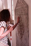 sehbehinderte Person tastet eine Marmorplatte mit Inschrift